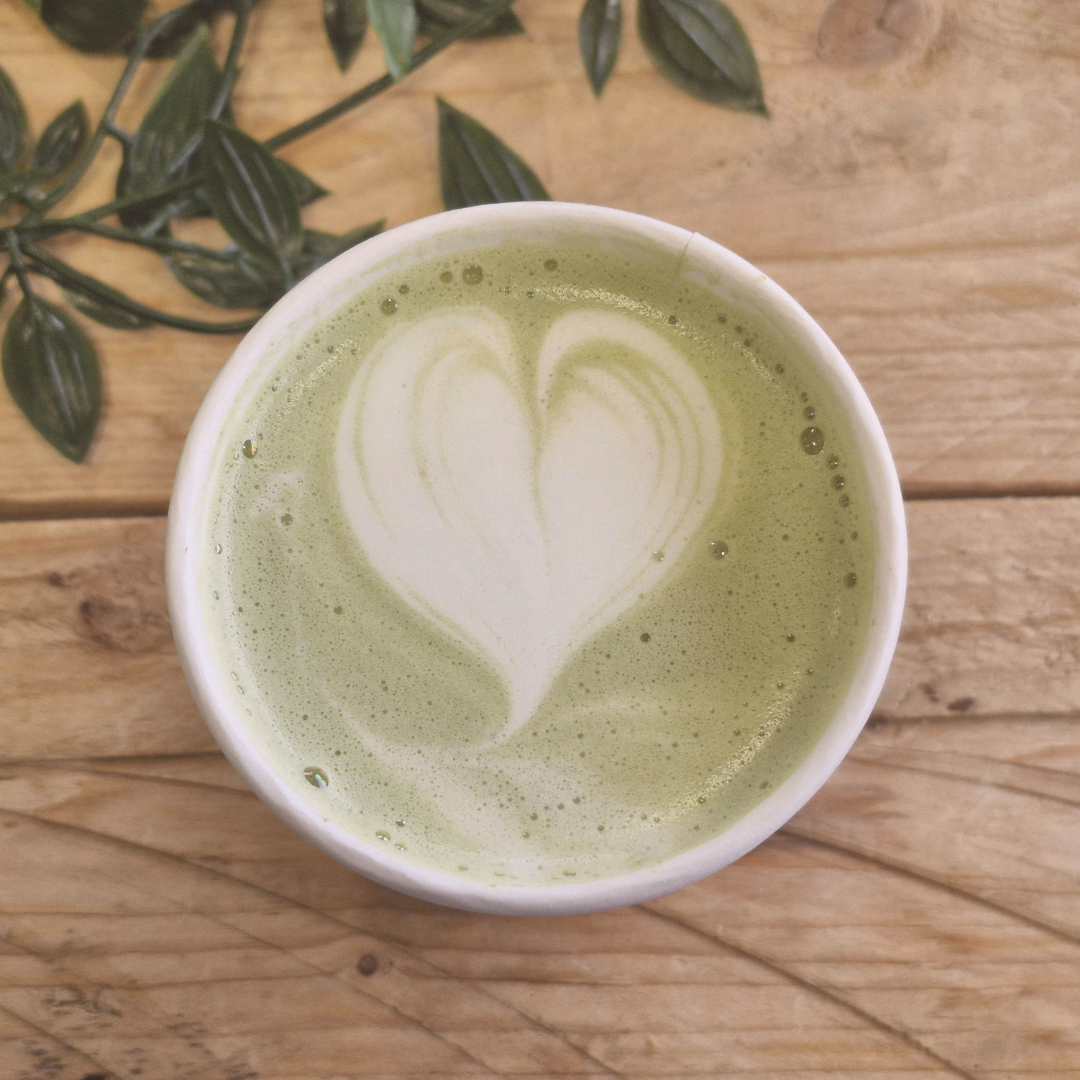 Matcha latte on a wood table with eucalyptus leaves