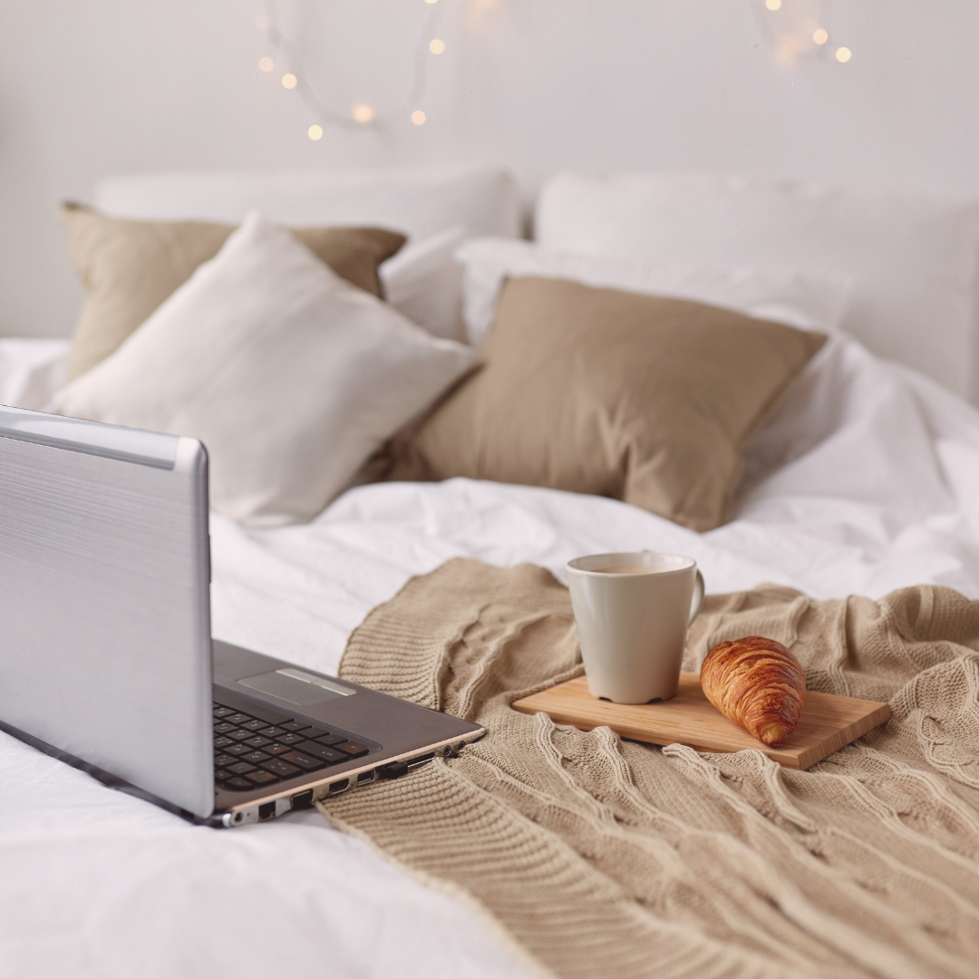A cozy laptop and coffee on a bed