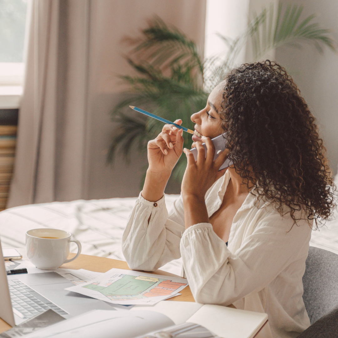 A woman on the phone at her desk with coffee